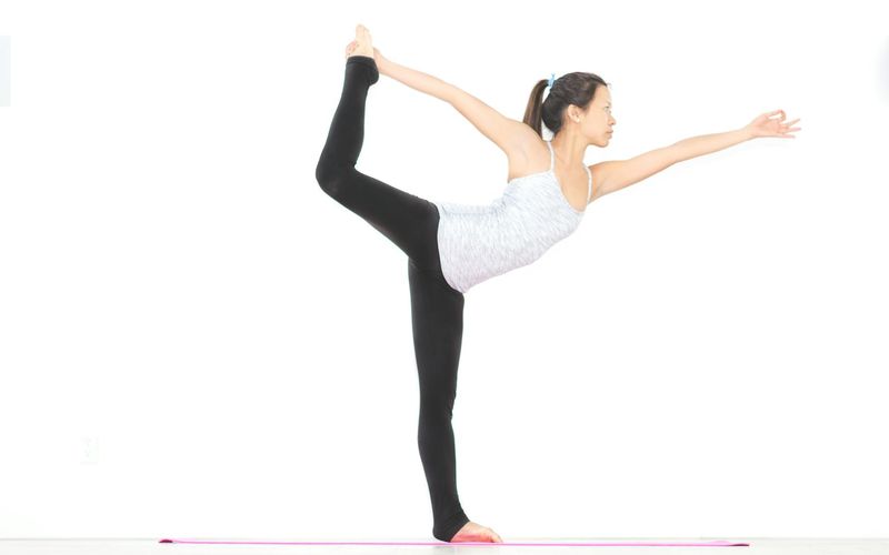 Person performing a balanced yoga movement on a mat.